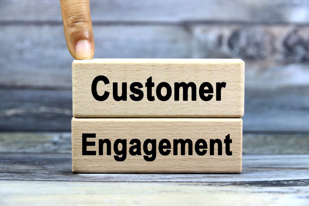 "Customer" and "engagement" written on stacked of wood blocks with a finger pointing at it.