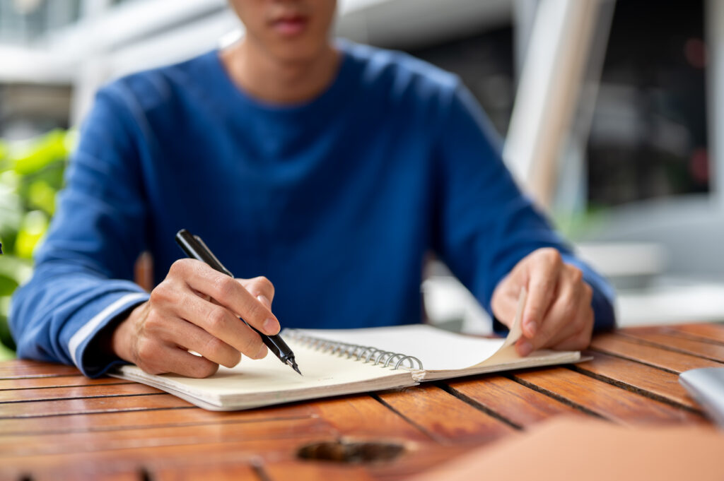 A person writing his professional growth plan in his notebook.